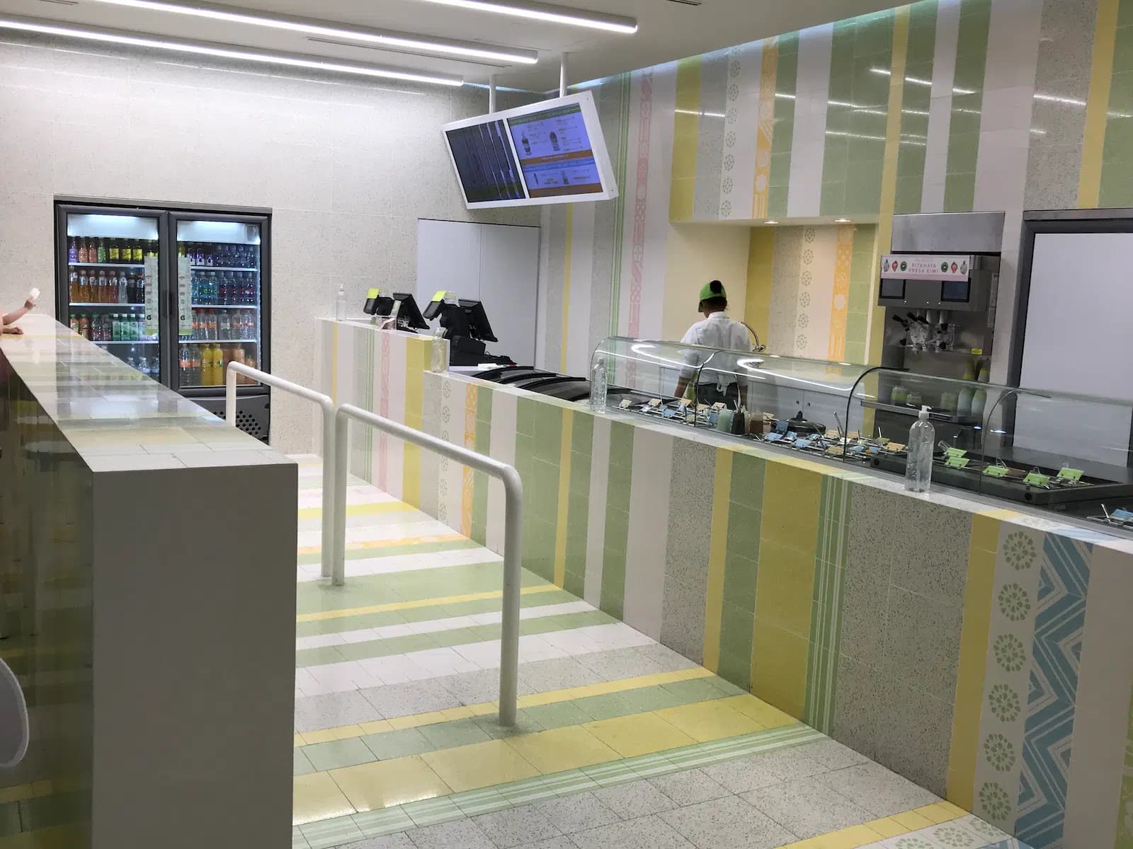 Interior de nevería con mostrador blanco, vitrina de helados y azulejos en tonos pastel