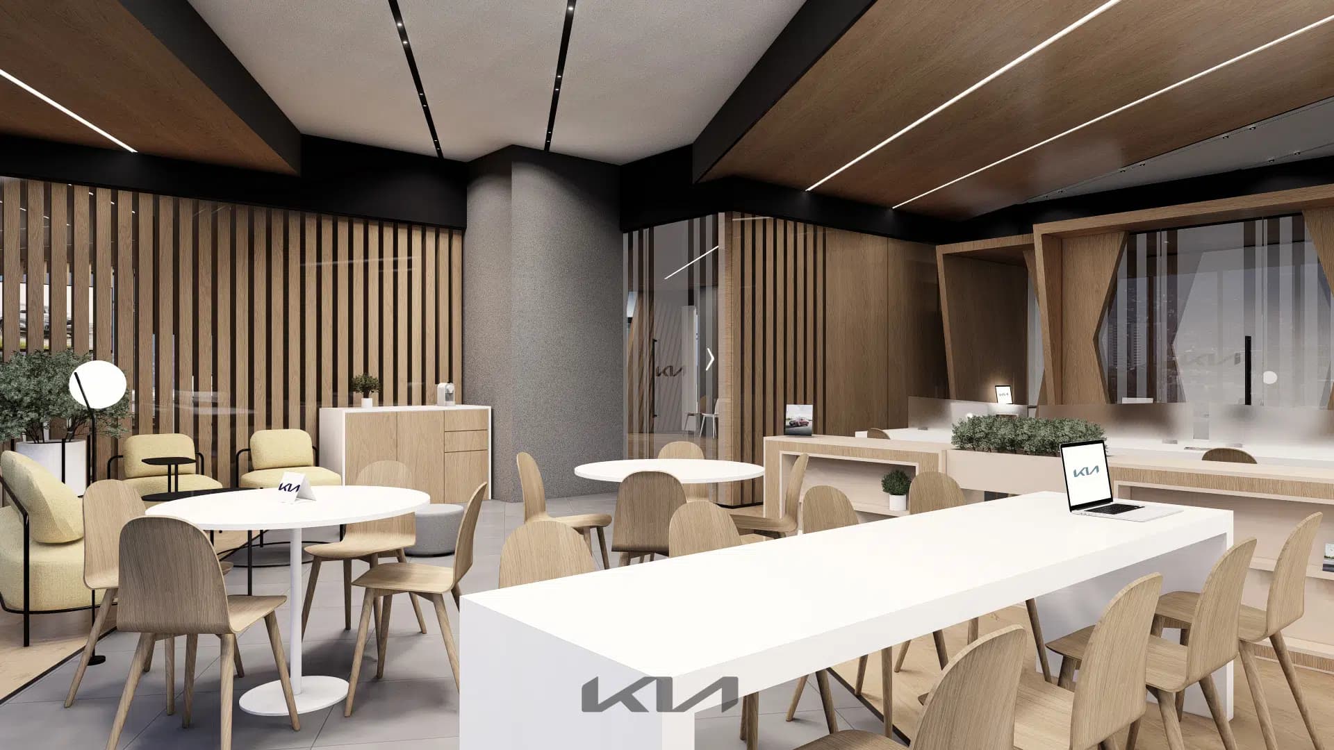 Área colaborativa de oficinas KIA con mesa comunal, sillas de madera y lounge